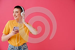 Young woman in headphones smiling and using mobile phone