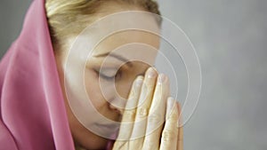 Young woman in headscarf is praying. close-up female hands holding chain with a cross