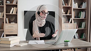 Young woman in headset having video call with partners, working process at office.