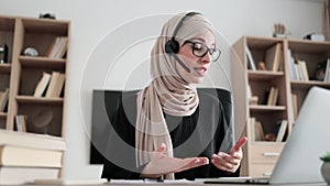 Young woman in headset having video call with partners, working process at office.