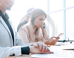 young woman with a headset on is working in an office.