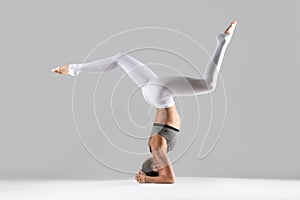 Young woman in headstand pose, grey studio background