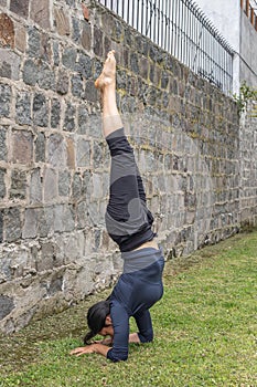 Young woman headstand in yoga salamba sirsasana position outdoors