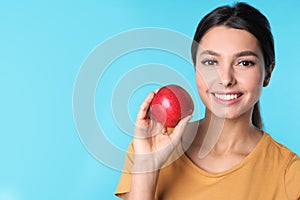 Young woman with healthy teeth and apple on color background