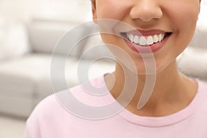 Young woman with healthy teeth on blurred background, closeup. Space for text