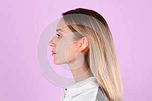 Young woman with hearing problem on pink background