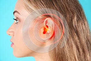 Young woman with hearing problem on turquoise background, closeup photo
