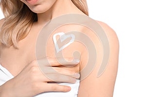 Young woman with heart made of cream on her shoulder against white background, closeup