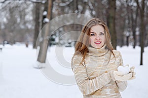 Young woman with a heart made of snow in her hands