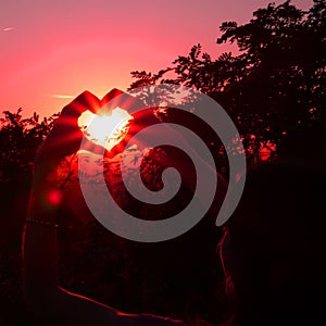 Young woman, heart and sunset