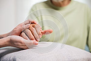 Young woman helping hands offering her senior man at home