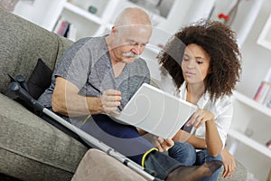 Young woman helping senior man with laptop computer