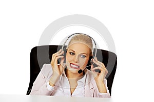 Young woman helpline operator is trying to hear something through a headphones