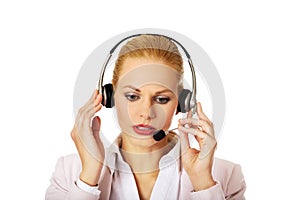 Young woman helpline operator is trying to hear something through headphones