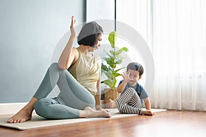 Young Woman and her adorable boy practicing yoga on yoga mat