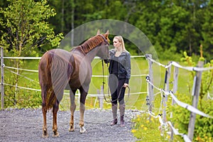 Young woman with her arabian horse standing at a riding course