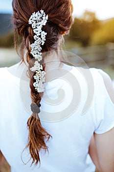 Young woman on her back, Female with hair in a braid with small white flowers looking at the sunset in the countryside. Beauty