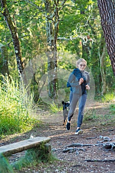 young woman and her big dog jogging in the forest paths