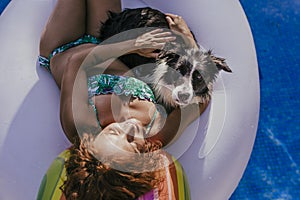 young woman and her border collie dog standing on an inflatable toy unicorn at the swimming pool. Summertime, fun and lifestyle