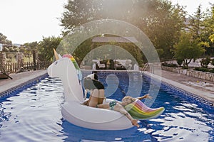 young woman and her border collie dog standing on an inflatable toy unicorn at the swimming pool. Summertime, fun and lifestyle