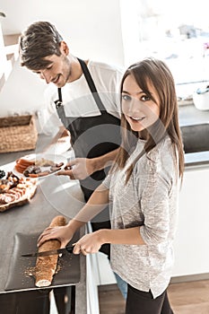 Young woman and her boyfriend are making sandwiches in the kitchen