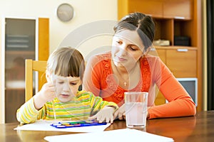 Young woman and her child painting with watercolor