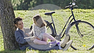 Young Woman with her Cute Daughter near bicycle in the park