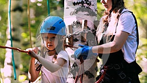 Young woman and her daughter crossing the rope bridge on an attraction in the park