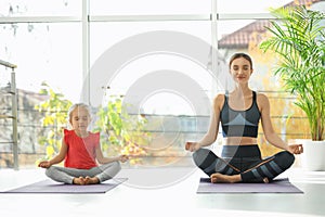 Young woman and her daughter doing exercise. Home fitness
