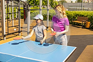 Young woman with her daughter playing ping pong in park