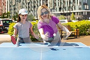 Young woman with her daughter playing ping pong in park