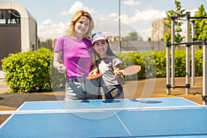 Young woman with her daughter playing ping pong in park