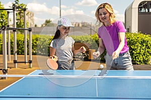 Young woman with her daughter playing ping pong in park