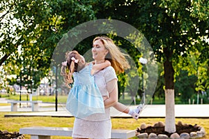 A young woman and her daughter are spinning in their arms. Mom and daughter are laughing and having fun