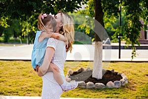 A young woman and her daughter are spinning in their arms. Mom and daughter are laughing and having fun