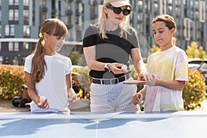 Young woman with her daughters playing ping pong in park