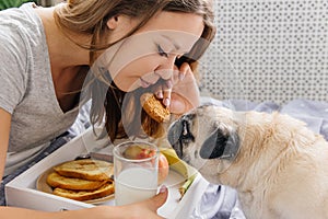 Young woman with her dog in a bed. Breakfast in bed