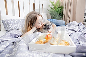 Young woman with her dog in a bed. Breakfast in bed