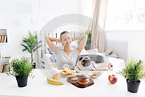 Young woman with her dog in a bed. Breakfast in bed