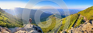 Young woman and her dog on mount Vuhaty Kamin. Panorama. Chornohora ridge, Carpathian mountains, Ukraine.