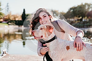 young woman and her dog outdoors in a park with a lake. sunny day, autumn season