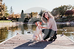 young woman and her dog outdoors in a park with a lake. sunny day, autumn season