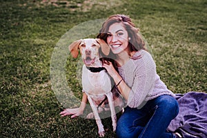 young woman with her dog at the park. she is hugging the dog. autumn season