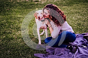 young woman with her dog at the park. she is hugging the dog. autumn season