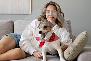 Young woman and her dog on sofa at home. Adorable pet.