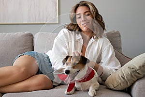 Young woman and her dog on sofa at home. Adorable pet.