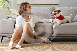 Young woman and her dog on sofa at home. Adorable pet.