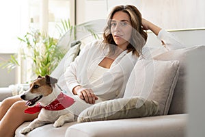 Young woman and her dog on sofa at home. Adorable pet.