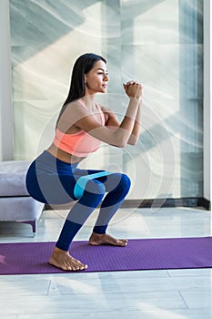 Young woman during her fitness workout at home with rubber resistance band