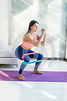 Young woman during her fitness workout at home with rubber resistance band